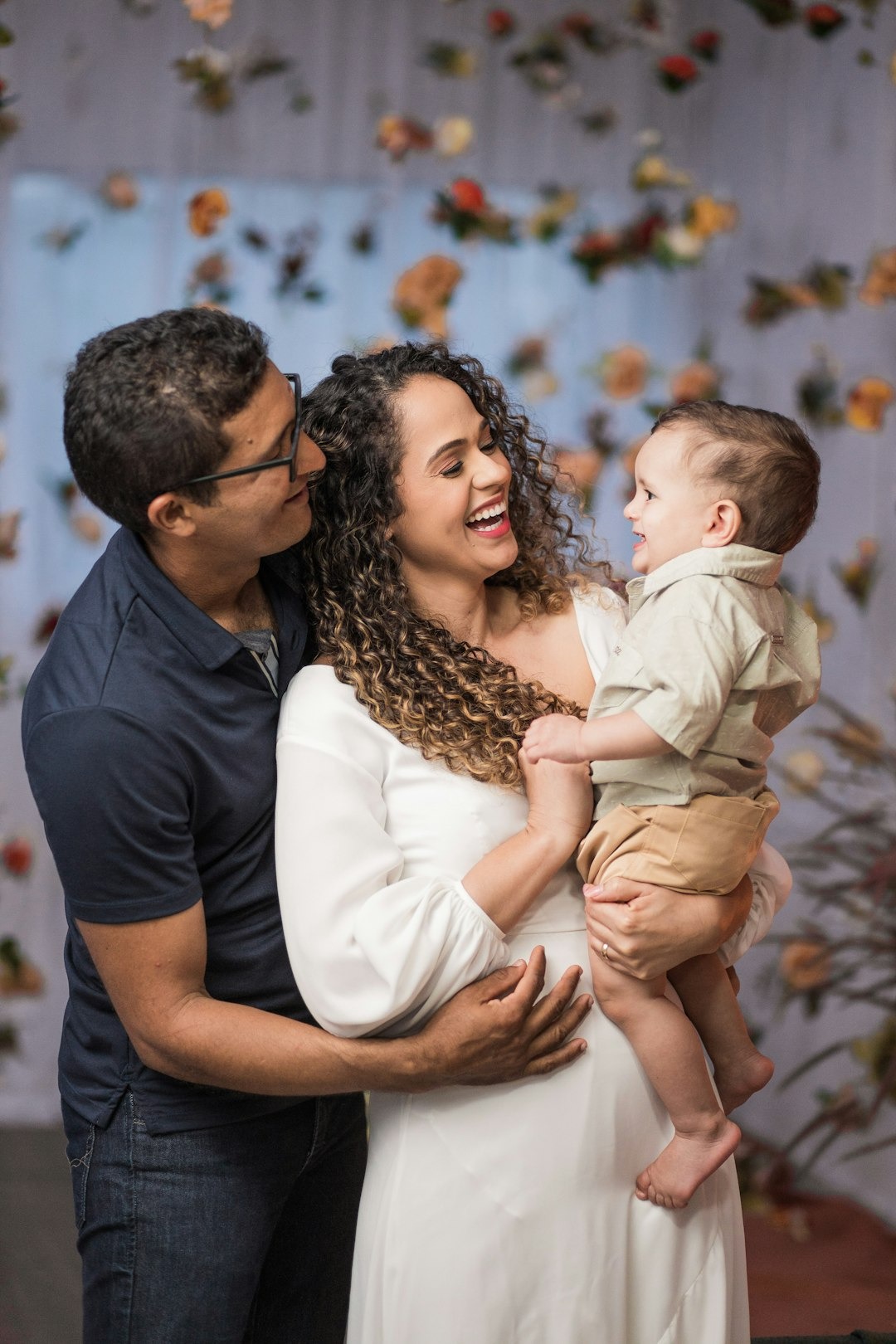 A family laughs together against a floral blue backdrop.